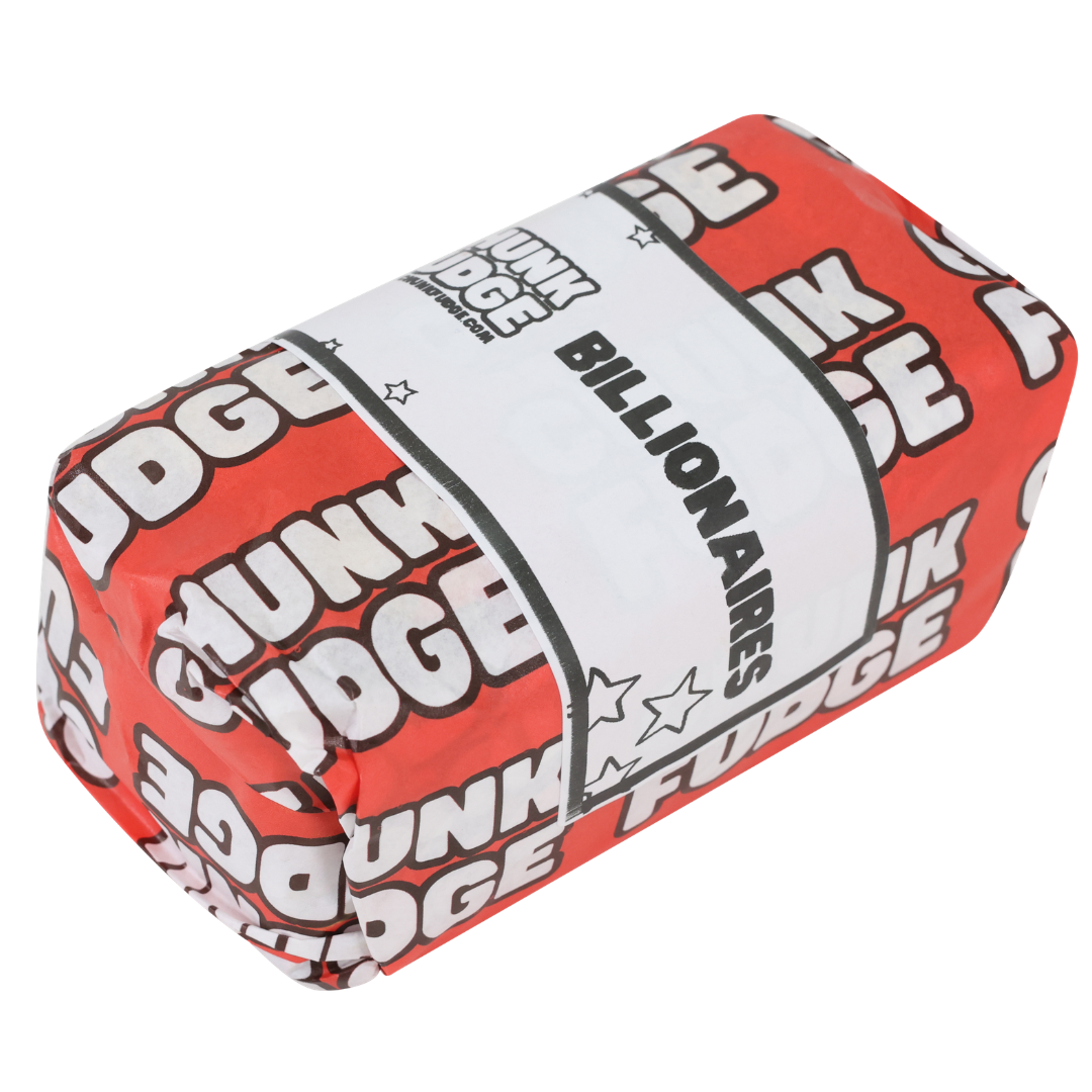 A red rectangular block wrapped with "CHUNK FUDGE" in white text and a bold white label across the center reading "BILLIONAIRES FUDGE" features an indulgent combination of salted caramel fudge.