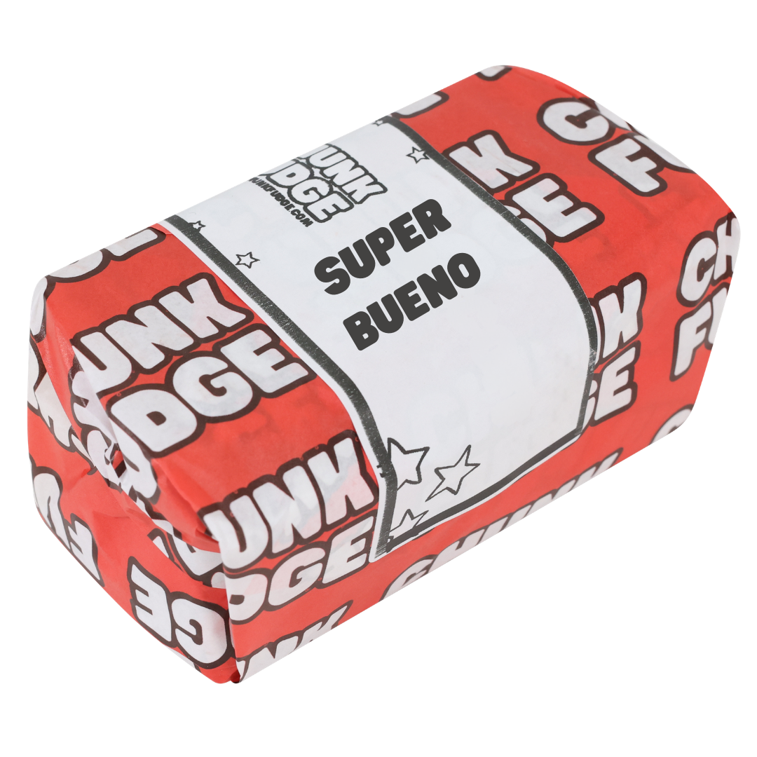 A rectangular food item wrapped in red and white paper labeled "CHUNK FUDGE" and "SUPER BUENO," with star designs, suggests a tasty Super Bueno Fudge treat.